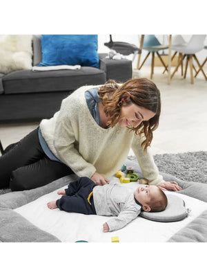 Gray baby head support cushion supporting an infant's head during floor time.