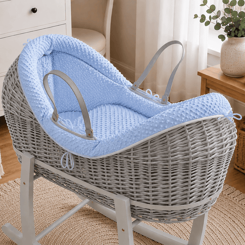 Grey wicker baby moses basket on white stand with padded blue waffle bedding