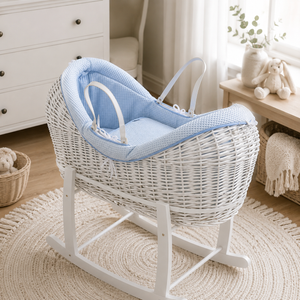White wicker baby crib with blue cushion in a nursery setting