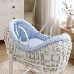 White wicker baby crib with blue cushion in a nursery setting