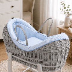 Grey wicker baby moses basket on white stand with padded light blue waffle bedding