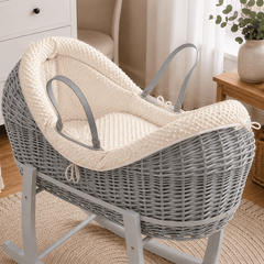 Grey wicker baby moses basket on white stand with padded cream waffle bedding