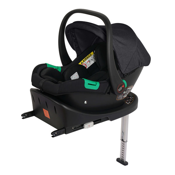 Black infant car seat with canopy and green handle, shown on a matching base