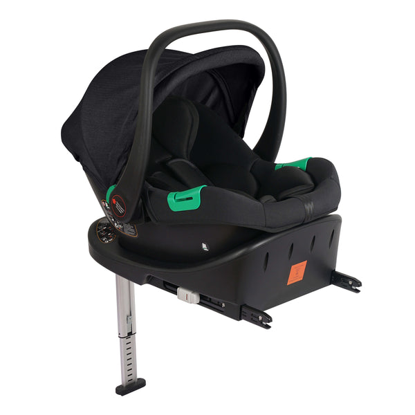 Black infant car seat with canopy and green handle, side view on the base