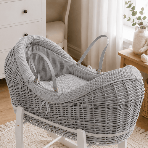 Grey wicker baby moses basket on white stand with padded cream waffle bedding