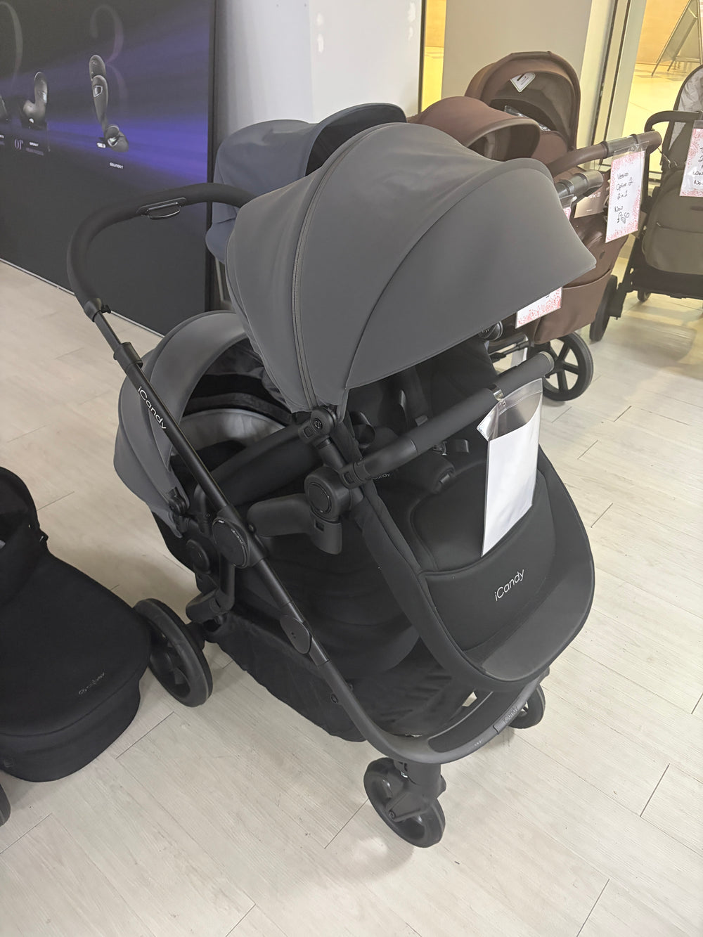 Grey pushchair with attached carrycot and seat, front three-quarter view, stroller wheels