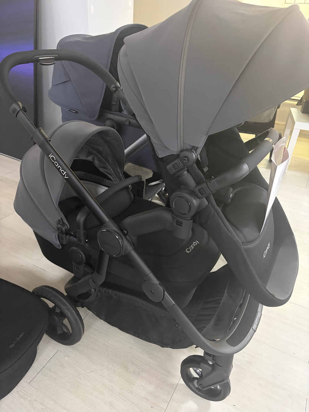 Grey pushchair with attached carrycot and seat, front three-quarter view, stroller wheels