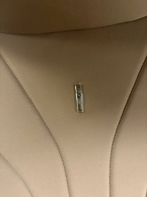 Venicci Claro carrycot fabric close-up with logo tag on tan upholstery