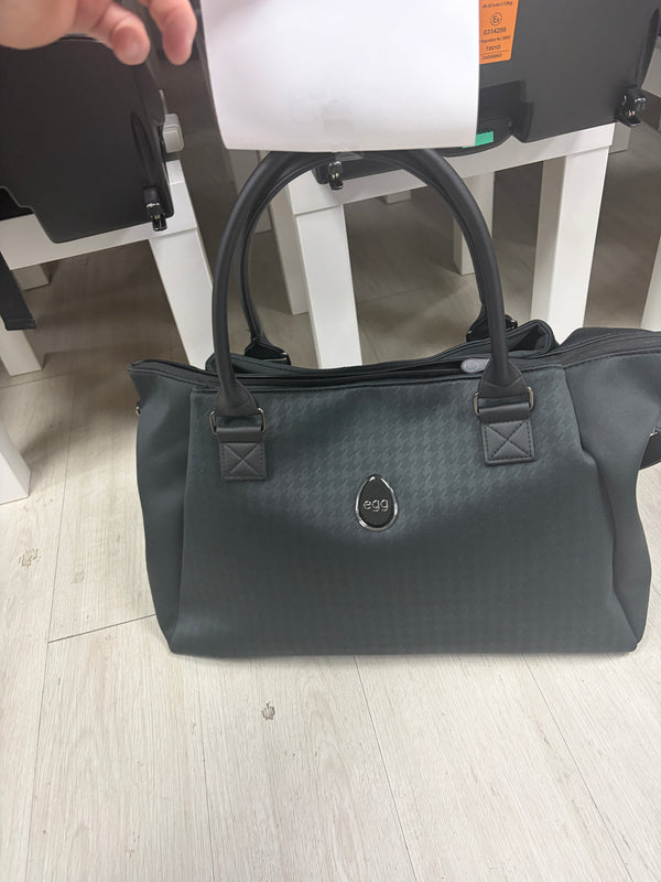 Dark overnight bag with top handles, front logo badge, and textured fabric