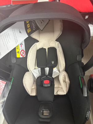 Newborn car seat with beige padding and black harness straps, close front view