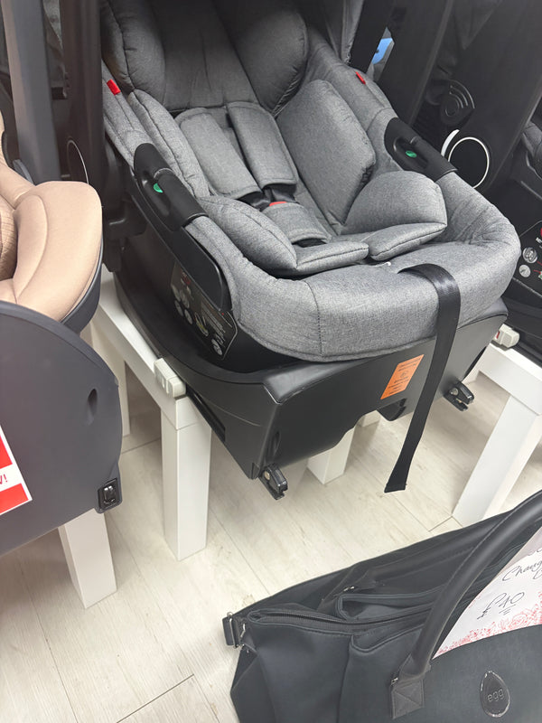 Grey newborn car seat with canopy handle, installed on ISOFIX base, side view