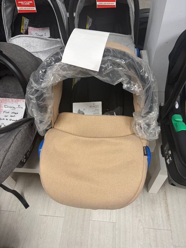 Cream newborn car seat with padded insert, wrapped in protective plastic