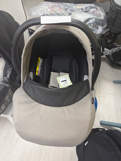 Beige newborn car seat carrier with black canopy and safety harness, front view
