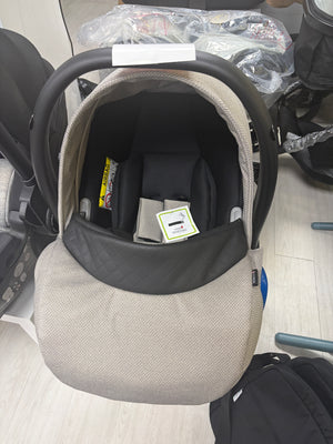 Beige newborn car seat carrier with black canopy and safety harness, front view