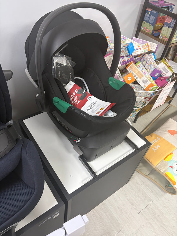 Black Cybex infant car seat with base and carry handle, angled view