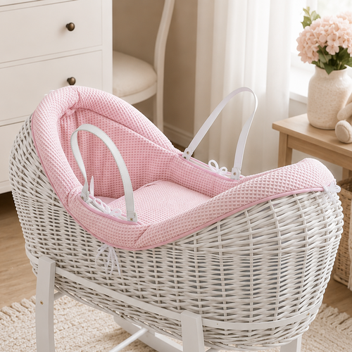 White wicker baby crib with pink cushion in a nursery setting