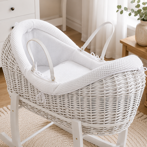 White wicker baby crib in a nursery with toys and decor.