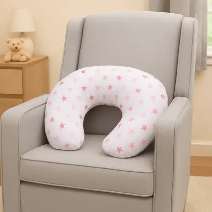 U-shaped pillow with pink star pattern on a gray chair in a cozy room.