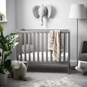 Taupe grey baby cot with vertical slats, raised rail, grey padded mattress, blanket