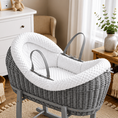 Gray wicker baby cradle with white cushion in a nursery setting