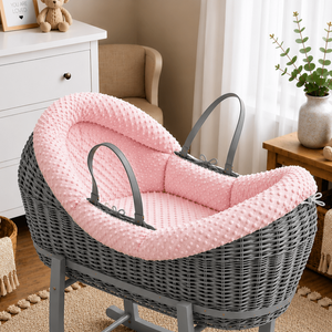 Gray wicker baby crib with pink cushion in a nursery setting