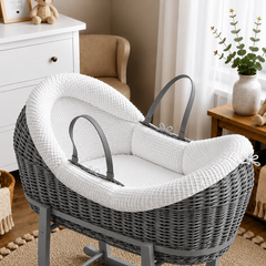Gray wicker baby crib with white cushion in a nursery setting