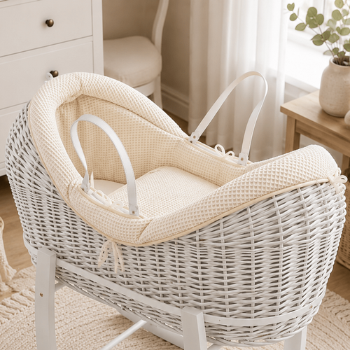 White wicker baby Moses basket with rocking stand in a nursery setting.