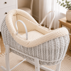 White wicker baby crib with beige cushion in a nursery setting