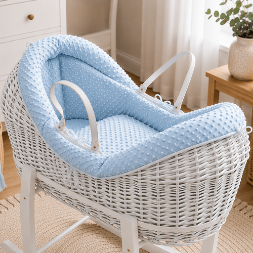 White wicker baby Moses basket with blue padding in a nursery setting.