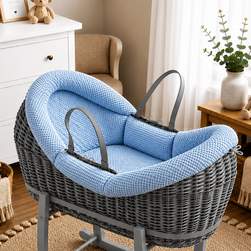 Gray wicker baby crib with blue cushion in a nursery setting