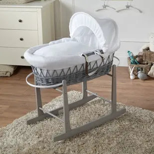 White wicker Moses basket with hood on a wooden stand in a nursery setting.